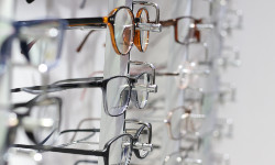 Rows of eyeglasses displayed on a transparent rack in a store.